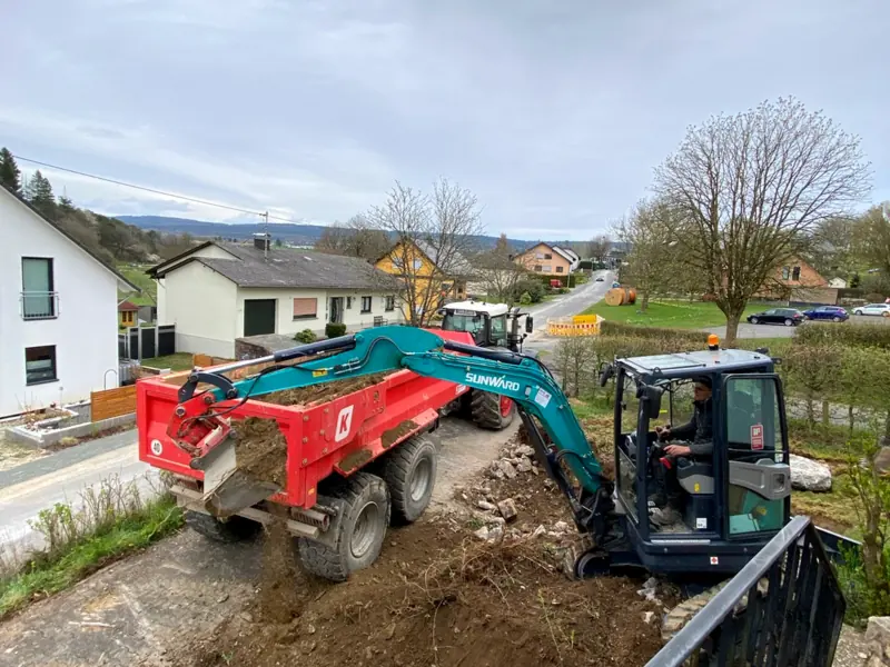 Bagger belädt einen Anhänger mit Aushub