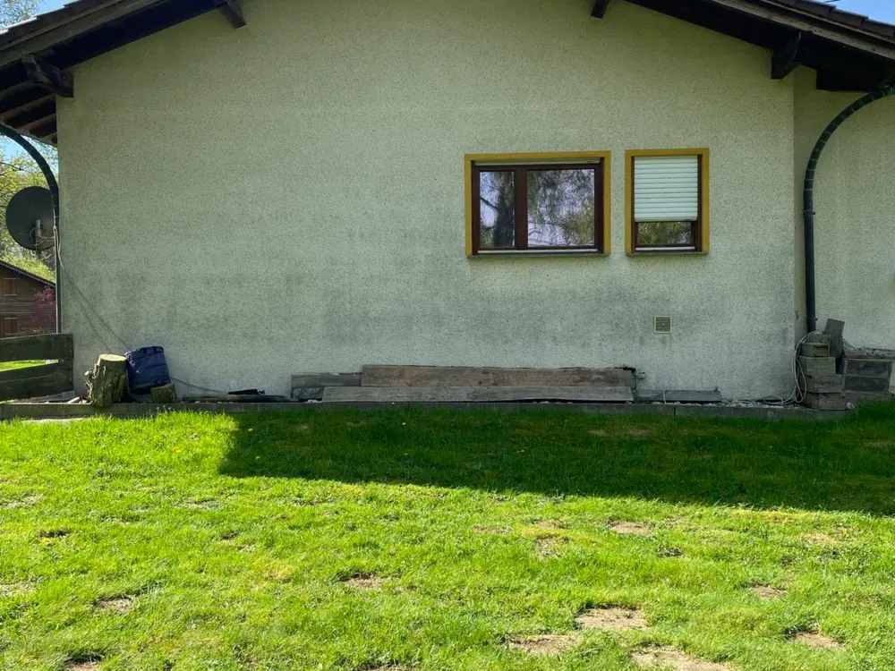 Hausfassade vor der Reinigung, verschmutzt mit Algen und Grünbelag