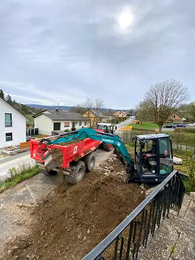 Bagger belädt einen Anhänger mit Aushub